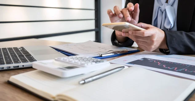 Empresária trabalhando e planejando em projeto de marketing de negociação de investimentos e usando calculadora para analisar gráfico de dados de uma bolsa de valores para o lucro do negócio financeiro