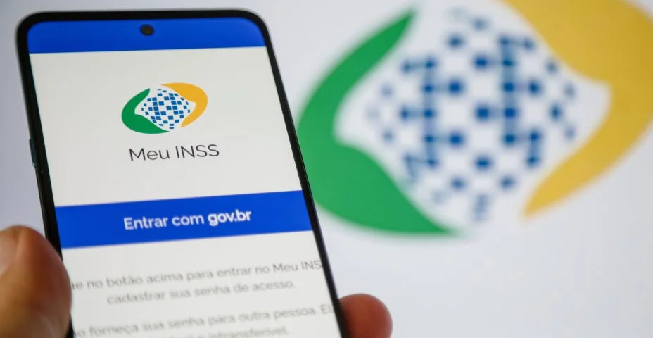 Aplicativo INSS para consultar seus beneficios na tela de um celular com fundo desfocado.