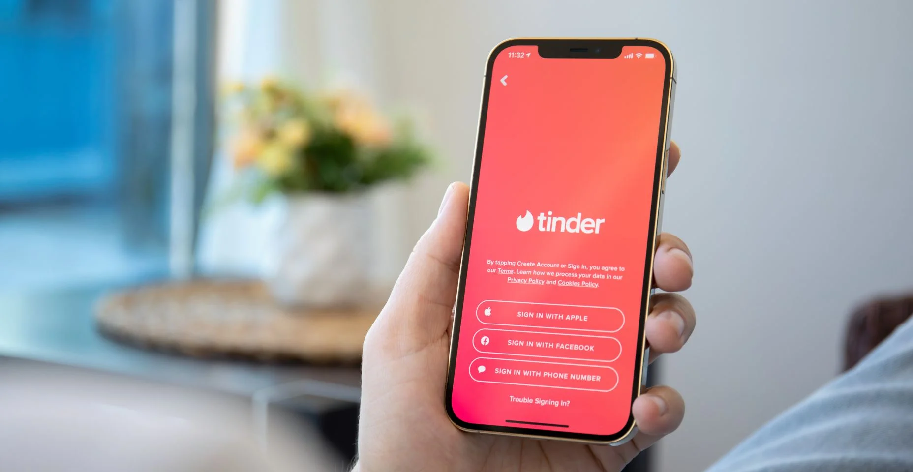 Mãos de homem segurando um iPhone 12 Pro Max Gold com Tinder aberto