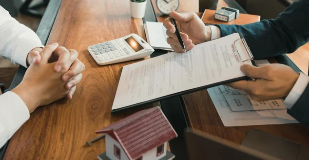 Os agentes usam canetas apontando para contratos e são explicados aos clientes no escritório.