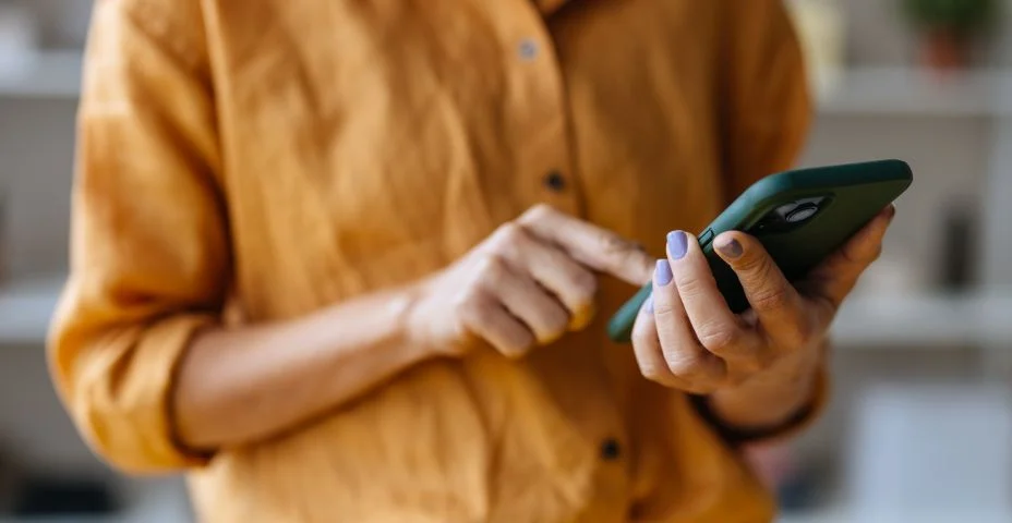 Uma empresária irreconhecível usando seu celular enquanto trabalha no escritório