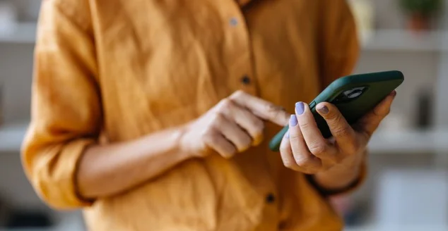 Uma empresária irreconhecível usando seu celular enquanto trabalha no escritório