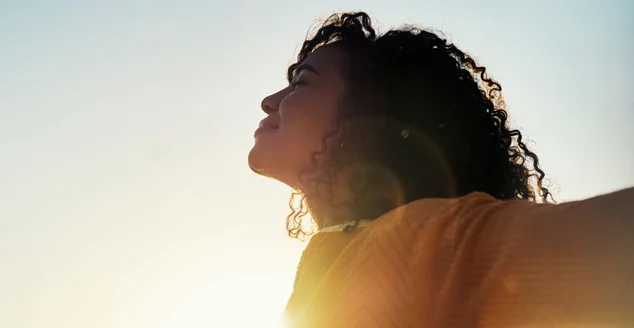 Liberdade, brilho e céu com uma mulher ao ar livre ao pôr do sol durante o verão para relaxar com ar fresco e sol. Feliz, despreocupada e maquete com uma jovem mulher se sentindo relaxada do lado de fora pela manhã