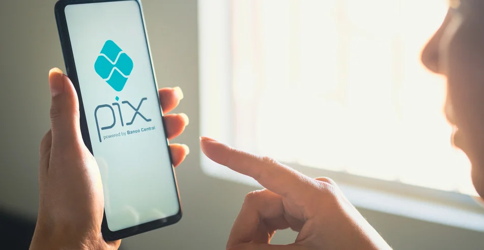 Nesta ilustração fotográfica, uma mulher segura um smartphone com o logotipo do PIX exibido na tela.