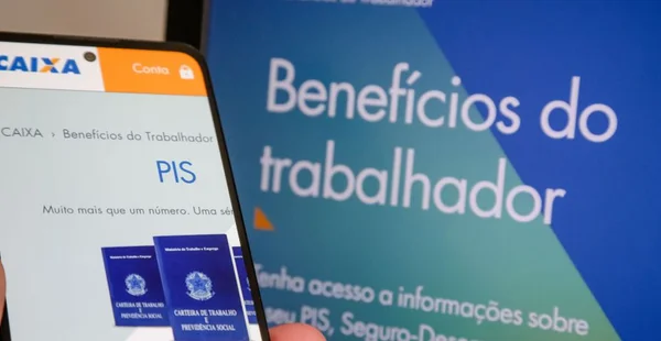 Mão segurando carteira de trabalho com dinheiro pis pasep do gorverno.