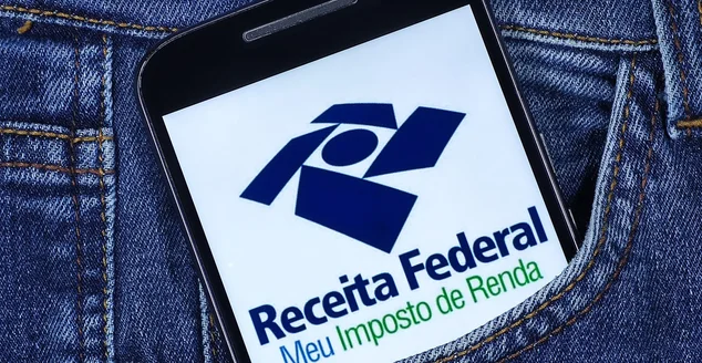 Logotipo do Meu Imposto de Renda na tela do smartphone no bolso da calça jeans.