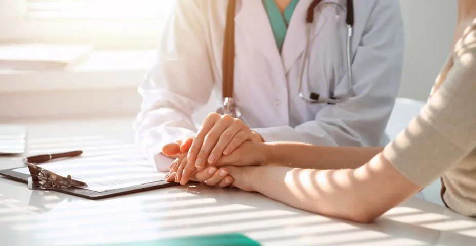 Doutor que tranquiliza a mulher paciente ao sentar-se na mesa na clínica, apenas mãos. Medicina e o melhor conceito do serviço