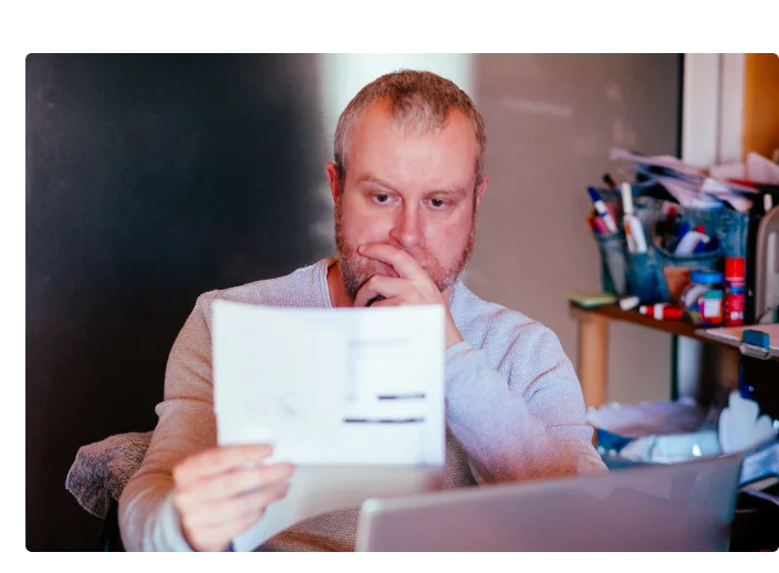 Homem sentado fazendo contas com o seus boletos caixa vencidos e vendo formas de efetuar o pagamento