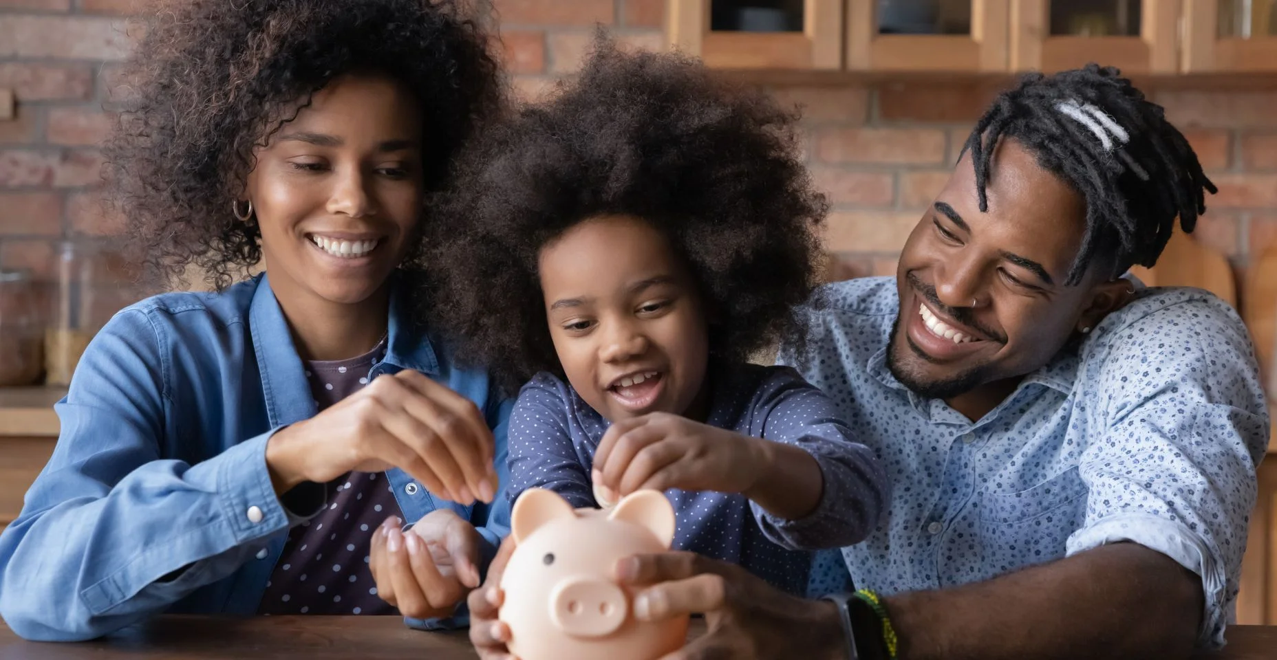 Pais jovens afro-americanos cuidando ensinando a filha pequena economizando dinheiro,