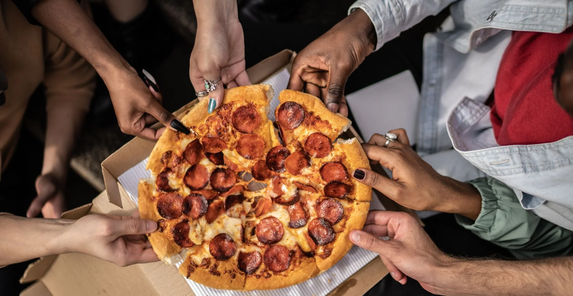 Mãos colhendo fatias de pizza