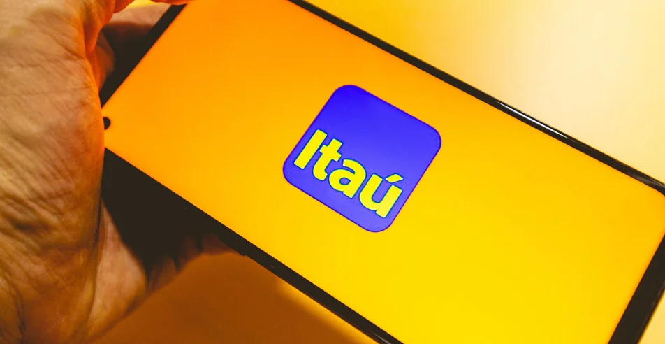 Um homem segurando com a mão um telefone celular com a logo do banco Itaú na tela. Banco, Serviço bancário, crédito, financiamento e ações na bolsa de valores do Brasil.