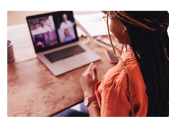 Mulher afro descendente participando de uma reunião virtual em sua mesa em casa