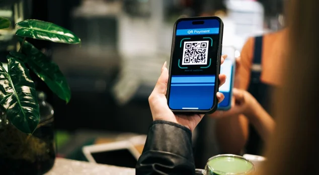 Close-up de um cliente usando o código QR para um pagamento sem dinheiro em um café, apresentando tecnologia moderna e conveniência. Ideal para temas de transações digitais e atendimento sem contato.