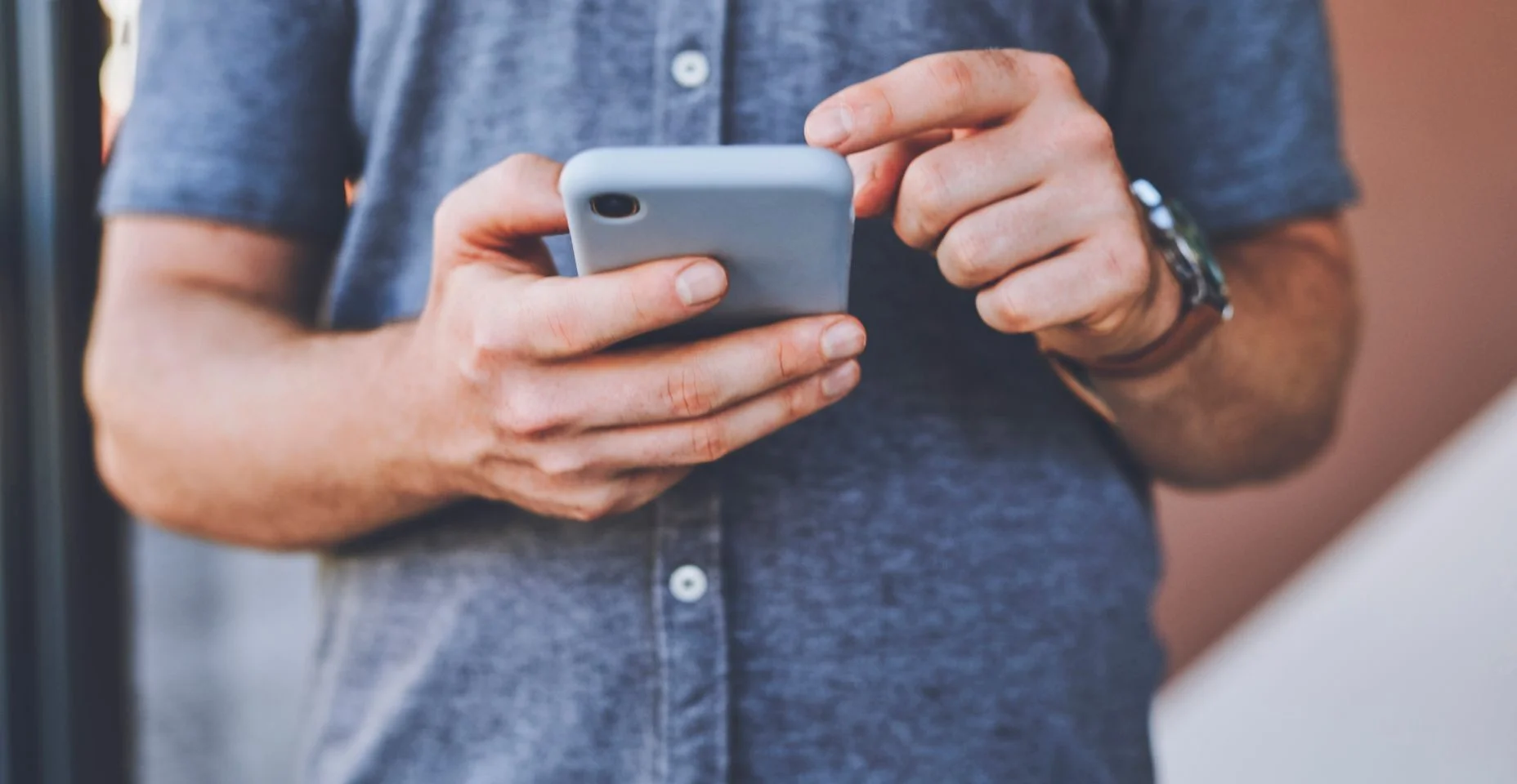 Close-up do homem mão em um telefone navegando nas redes sociais enquanto está ao ar livre na rua da cidade. Cara lendo um artigo ou blog em um site com um smartphone em uma estrada urbana da cidade.