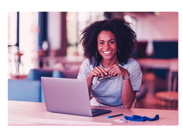 Mulher negra sentada olhando para frente com um notebook