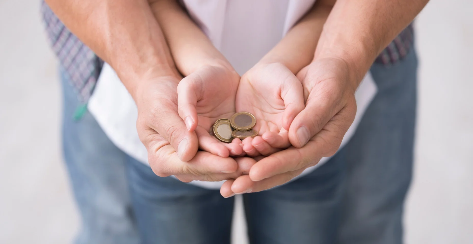 Pai e filha segurando moedas de euro.