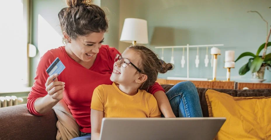 Mãe e filha em casa usando laptop para compras online