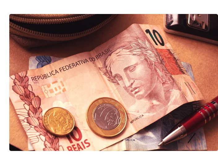 Notas e moedas brasileiras em um envelope de papel marrom.