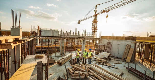 Canteiro de obras com três engenheiros e guindaste no topo de novo arranha-céu