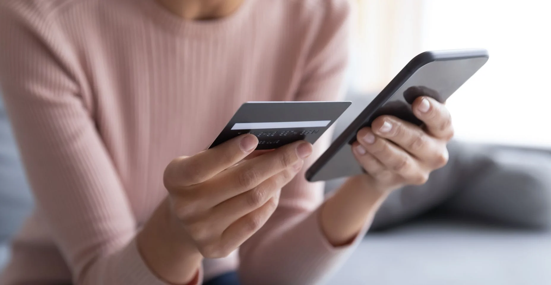 Feche as mãos femininas segurando cartão de crédito e smartphone