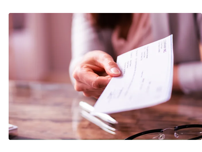 mulher segurando um cheque e entregando para outra pessoa