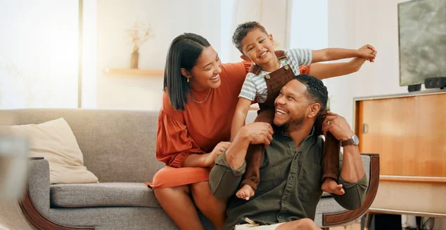 Uma família de três mestiços felizes relaxando no salão e sendo brincalhões juntos. Amar família negra se unindo com seu filho enquanto brincava de diversão no sofá de casa