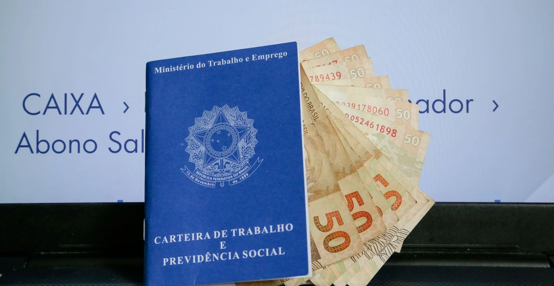 Carteira de trabalho com dinheiro ao redor