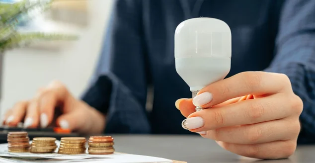 Mão feminina segurando uma lâmpada acima da mesa