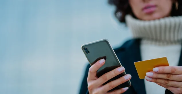 mãos de uma garota segurando um telefone inteligente e um cartão de crédito.