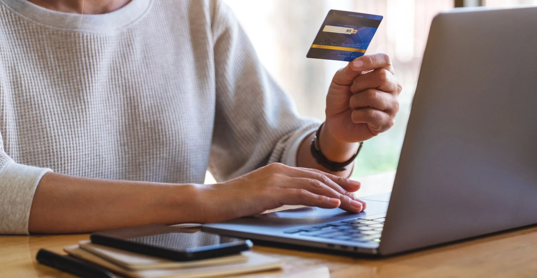 Uma mulher segurando cartões de crédito enquanto usa laptop computador no escritório