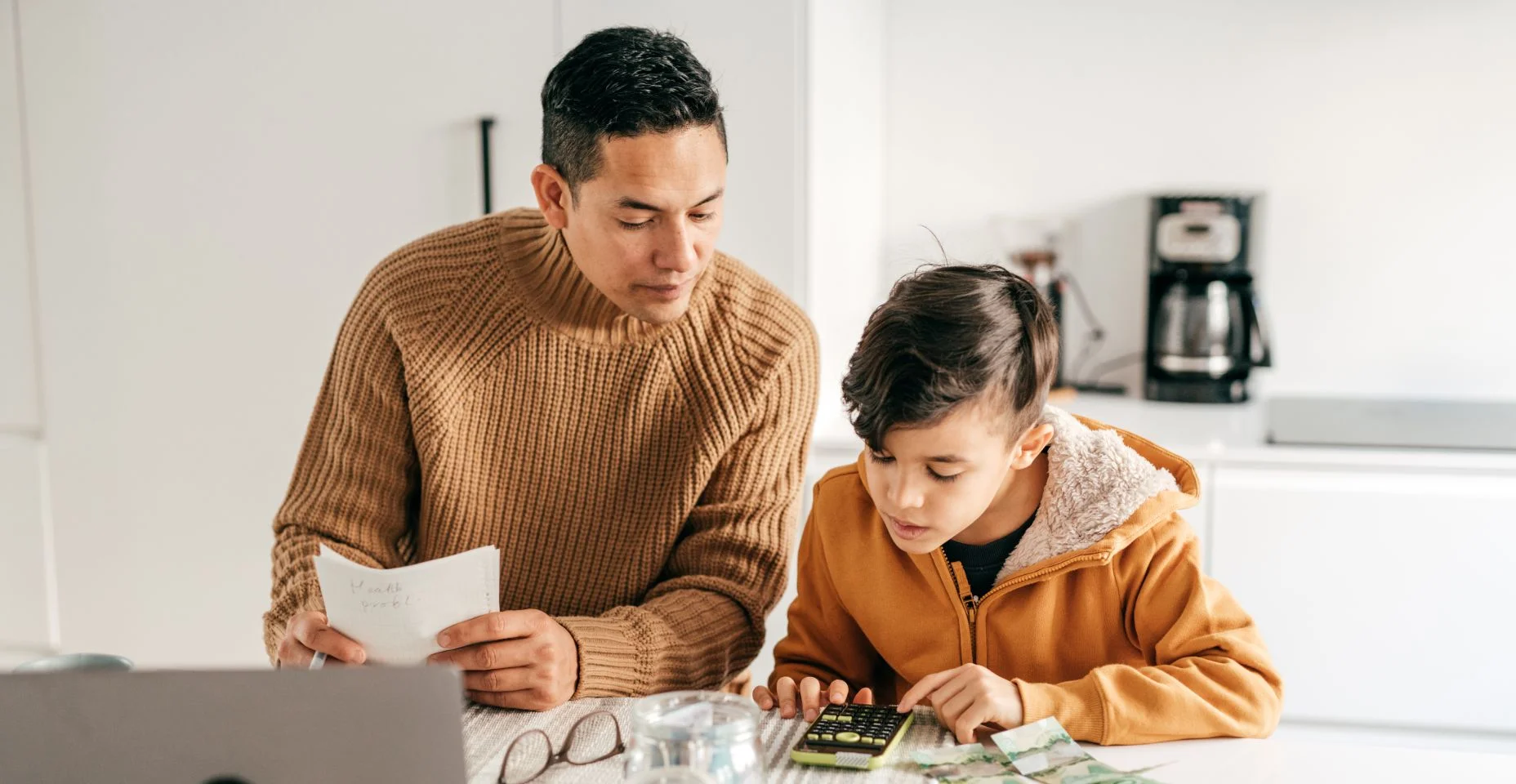 Pai e filho contando dinheiro com uma calculadora