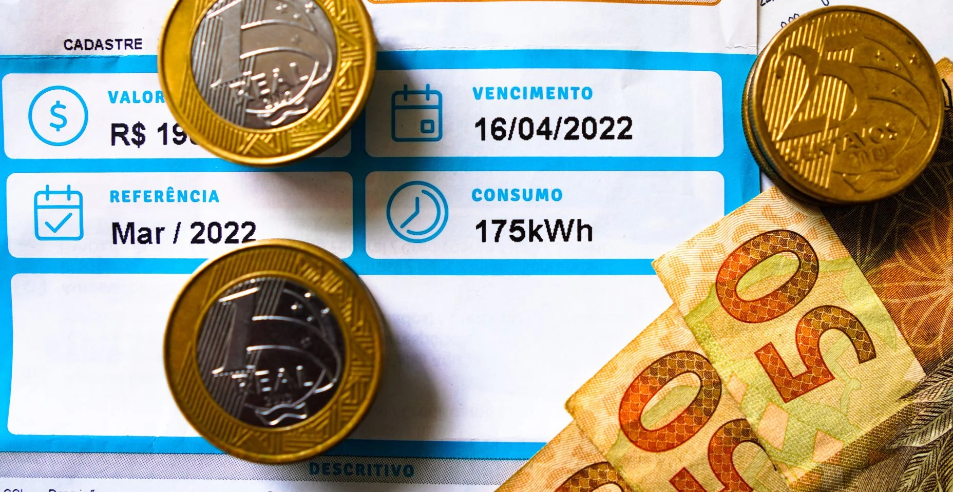 Uma conta de luz (energia elétrica), indicando o consumo mensal de 175 quilowatts-hora (kWh), com notas e moedas do Real brasileiro.