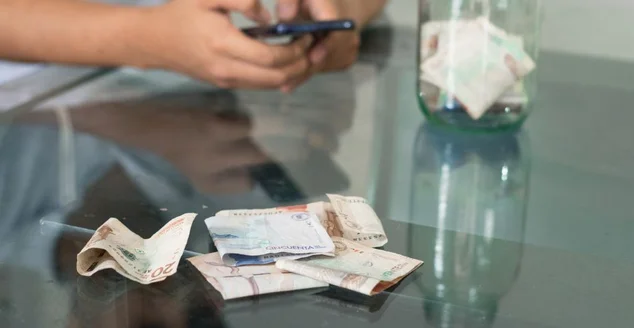 Homem fazendo compras online, situação financeira ruim, cara mandando sms no celular, notas na mesa, jovem falido, gastando suas economias. conceito econômico