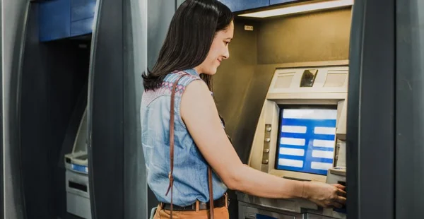 Mulher usando um distribuidor de dinheiro no banco