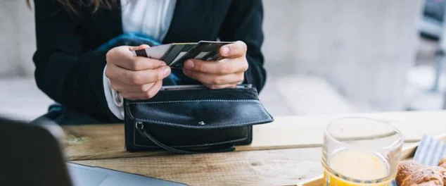 Mulher olhando seus cartões na bolsa para ilustrar artigo sobre conta santander e como ter limite com cartão de crédito