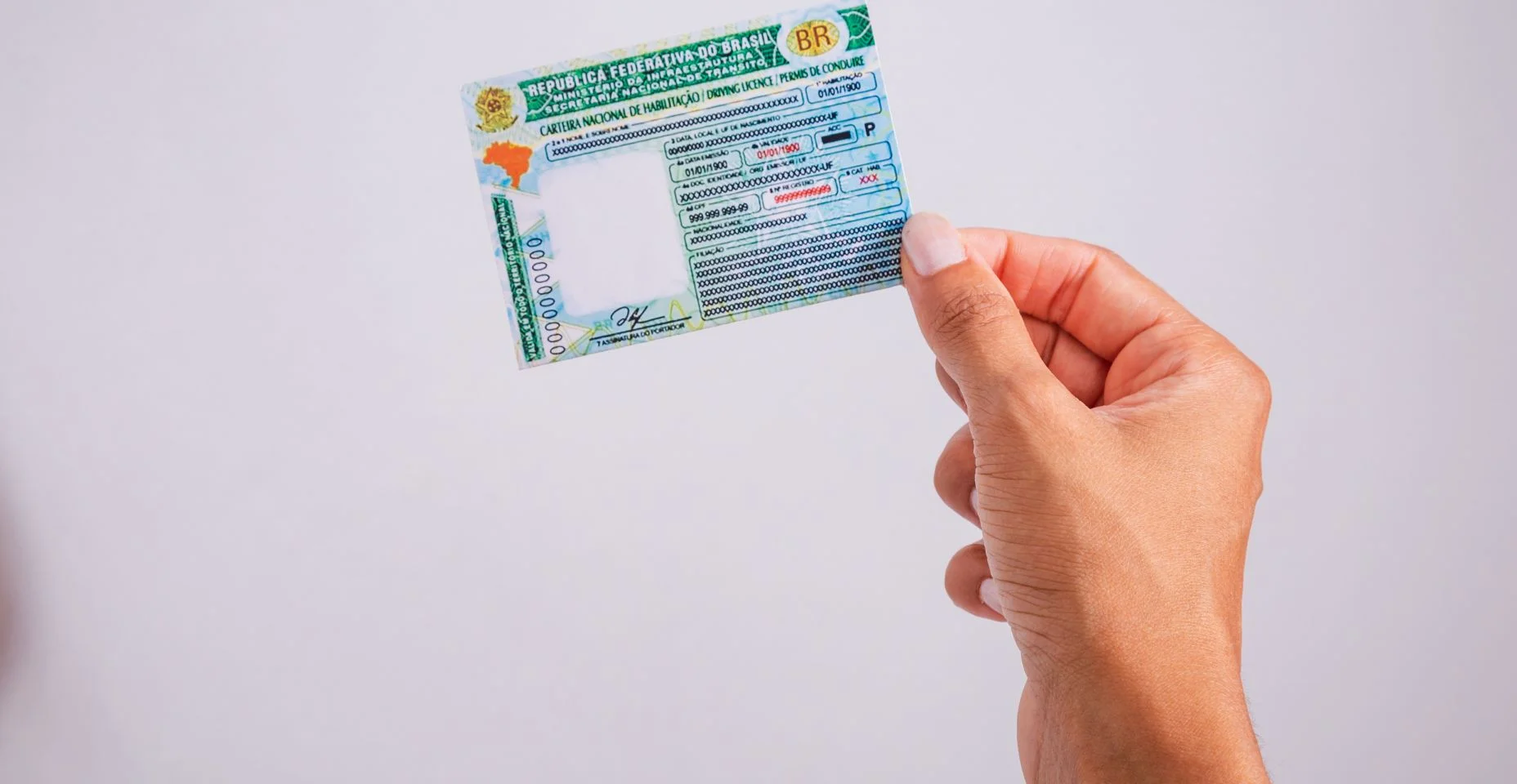 Mão segurando carteira de motorista. Documento brasileiro. Licenciada