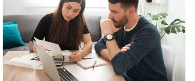 Casal com seu notebook olhando para ele para verificar dívida que caducou mas ainda está em oferta no limpa nome