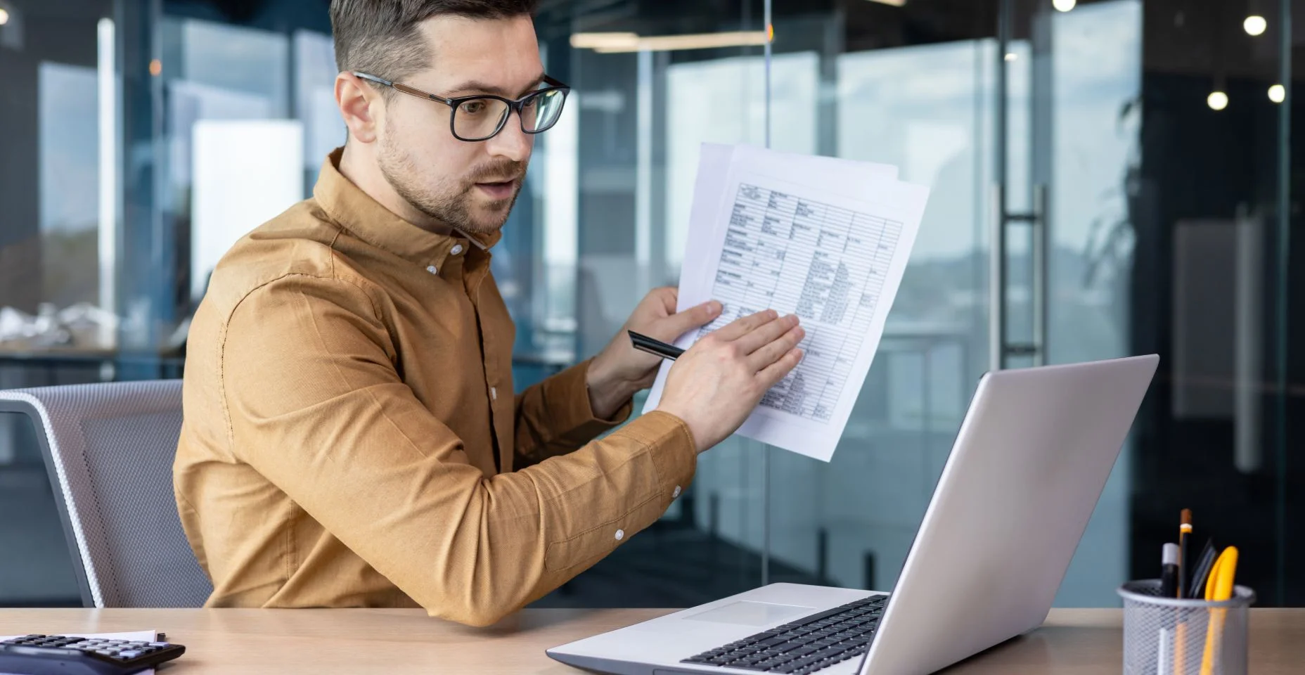 Um jovem empresário sério realiza treinamento de negócios on-line, uma conferência, sentado no escritório à mesa.