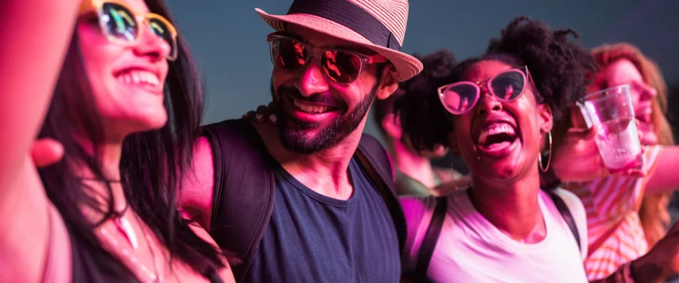 Pessoas sorrindo em um festival de música para ilustrar o artigo que fala sobre o que levar para um festival