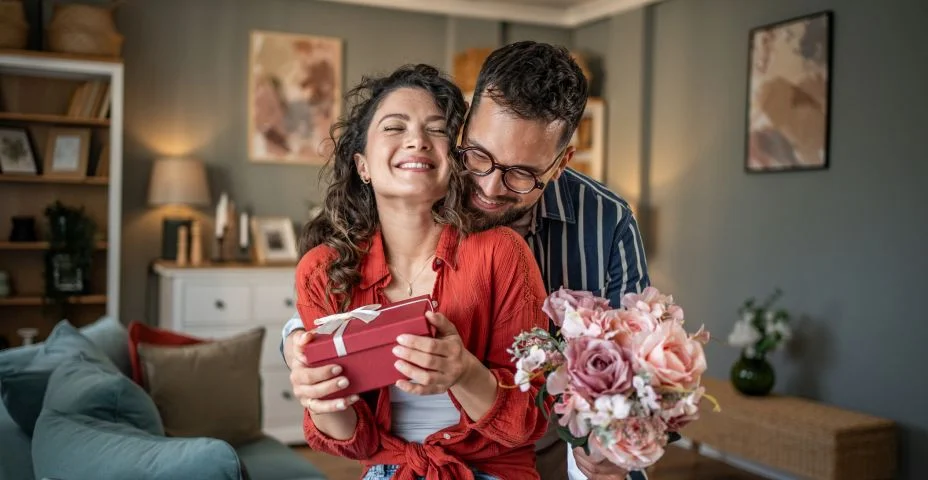 ovem surpreendendo sua namorada com um presente e flores em casa