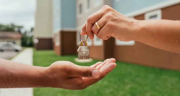 Detalhe das mãos do agente imobiliário entregando as chaves