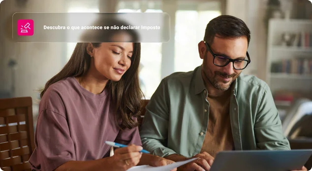 Casal sorridente trabalhando em relatórios e laptop em casa.
