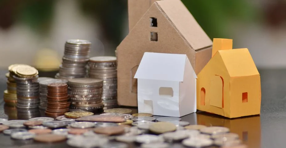 Casa de papel e pilhas de moedas em pé