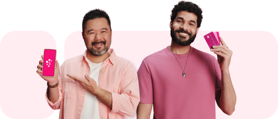 Duas pessoas vestidas de rosa. Uma das pessoas está segurando um celular com tela da Serasa e outra uma pessoa sorrindo segurando dois cartões de créditos