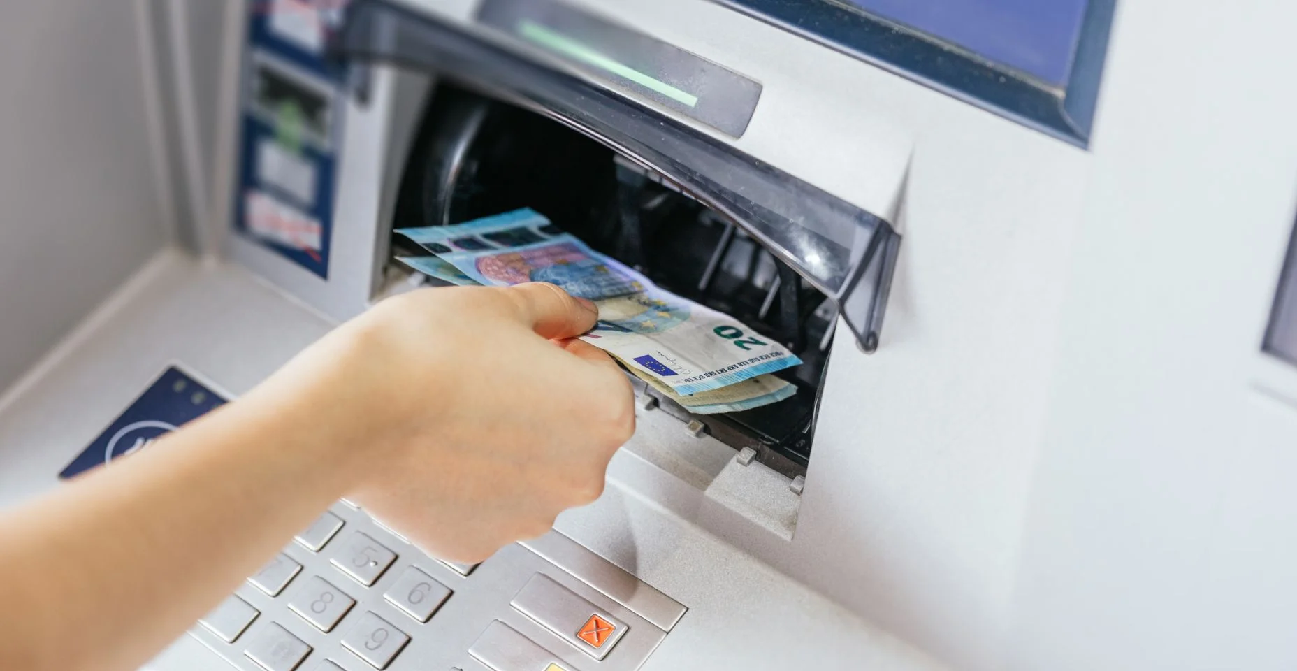 Perto da mão de uma mulher retirando dinheiro, notas de euro do caixa eletrônico.