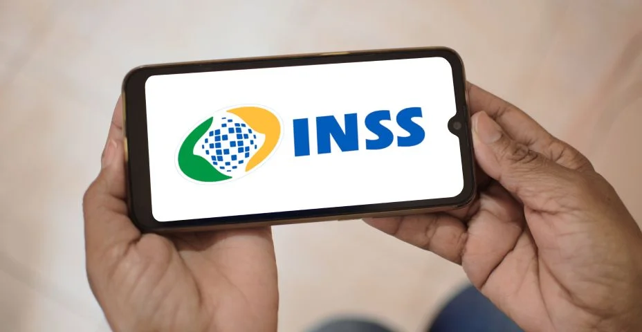 Instituto Nacional do Seguro Social. Aplicativo Meu INSS na tela de um celular que uma mulher segura.