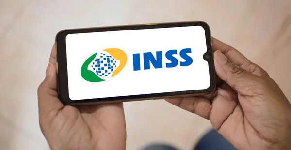 Instituto Nacional do Seguro Social. Aplicativo Meu INSS na tela de um celular que uma mulher segura.