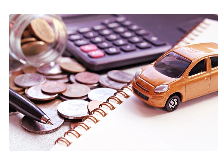 Modelo do carro em miniatura, calculadora, moedas espalhadas em frasco de vidro, papel de caderno e caneta na mesa de mesa de escritório
