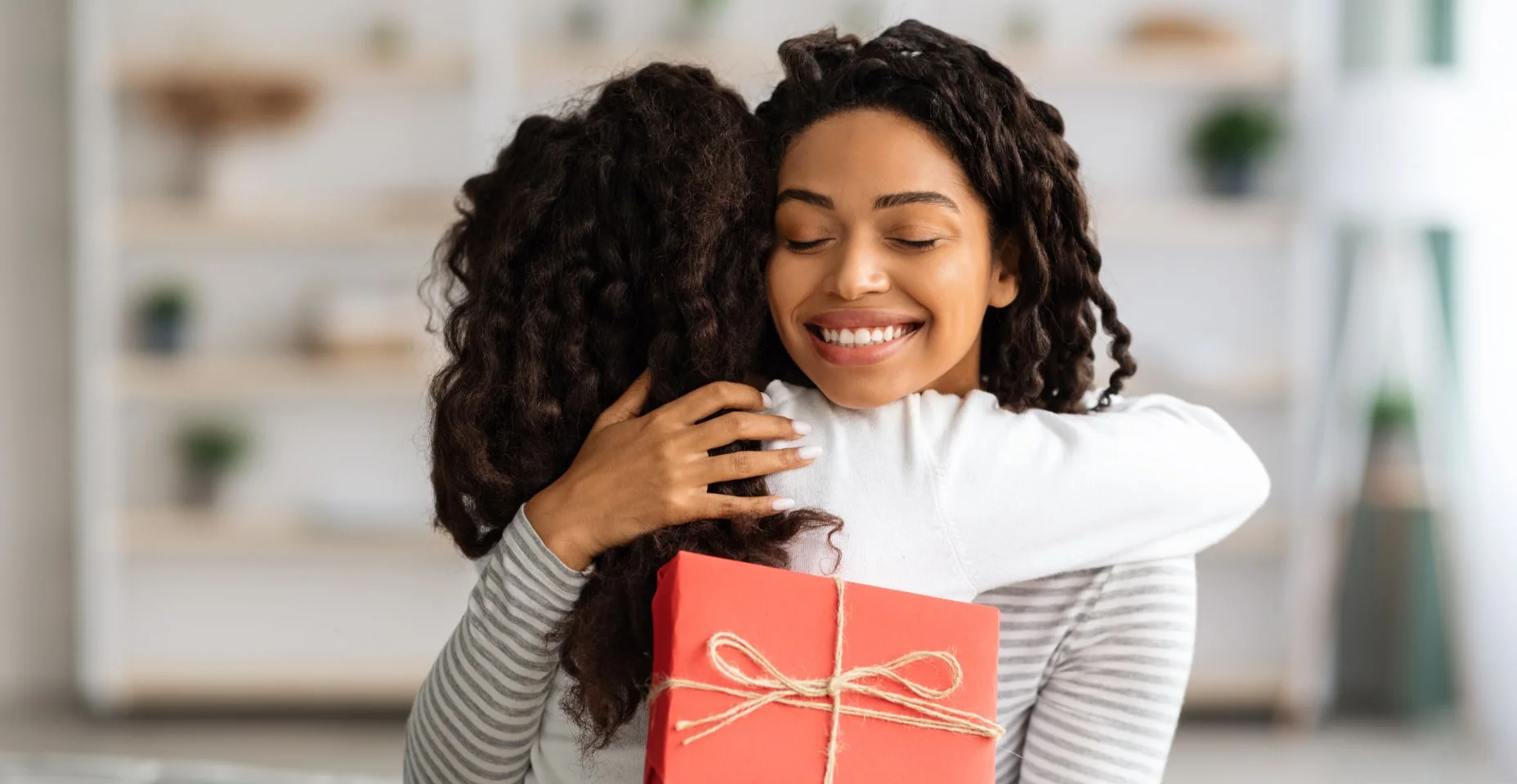 Mãe e filha se abraçando após receber presente para ilustrar artigo sobre como gastar pouco no dia das mães