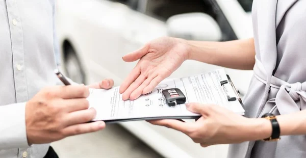 Negócio automotivo, venda de carros ou conceito de aluguel : Cliente feliz com agente de revendedor de carros fazendo acordo e assinando contrato de contrato de acordo em showroom de automóveis ou escritório de revendedor de carros.